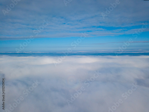 Aerial view. Flying over white clouds during the day in sunny weather. © Sergey