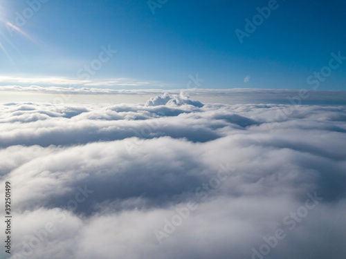 Aerial view. Flying over white clouds during the day in sunny weather. © Sergey