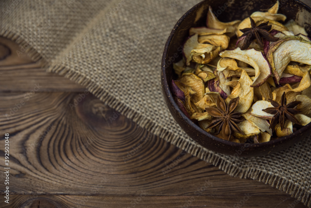 Homemade crispy sun dried organic apple slices. Close up of apple chips with spice in bowl on brown wooden background with copy space for text Homemade crispy sun dried organic apple slices. Close up of apple chips with spice in bowl on brown wooden background with copy space for text