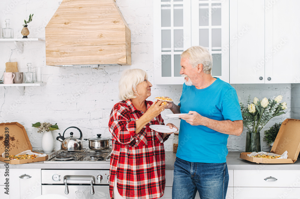 Senior couple eating pizza in the kitchen Senior couple eating pizza in the kitchen