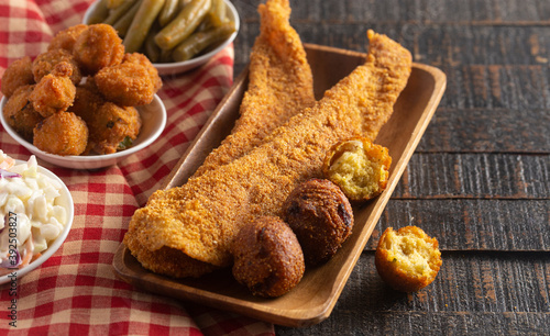 Photo Breaded and Fried Fillets of Fish with Hushpuppies on a Wooden Table
