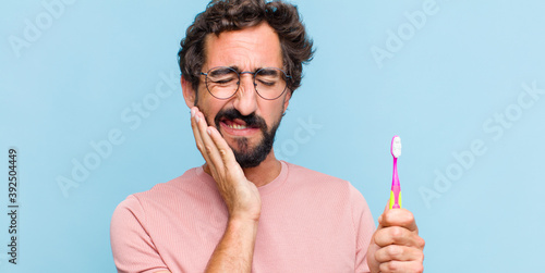Papier peint young bearded man holding cheek and suffering painful toothache, feeling ill, mi