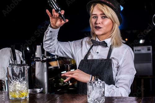 Girl barman creates a cocktail on the alehouse photo