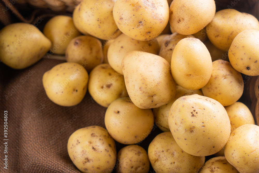 New raw potatoes in a wicker basket on a brown background close up New raw potatoes in a wicker basket on a brown background close up