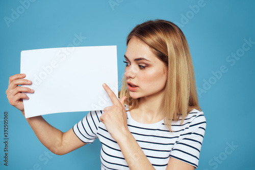 Woman holding sheet of paper striped T-shirt Copy Space cropped view blue background