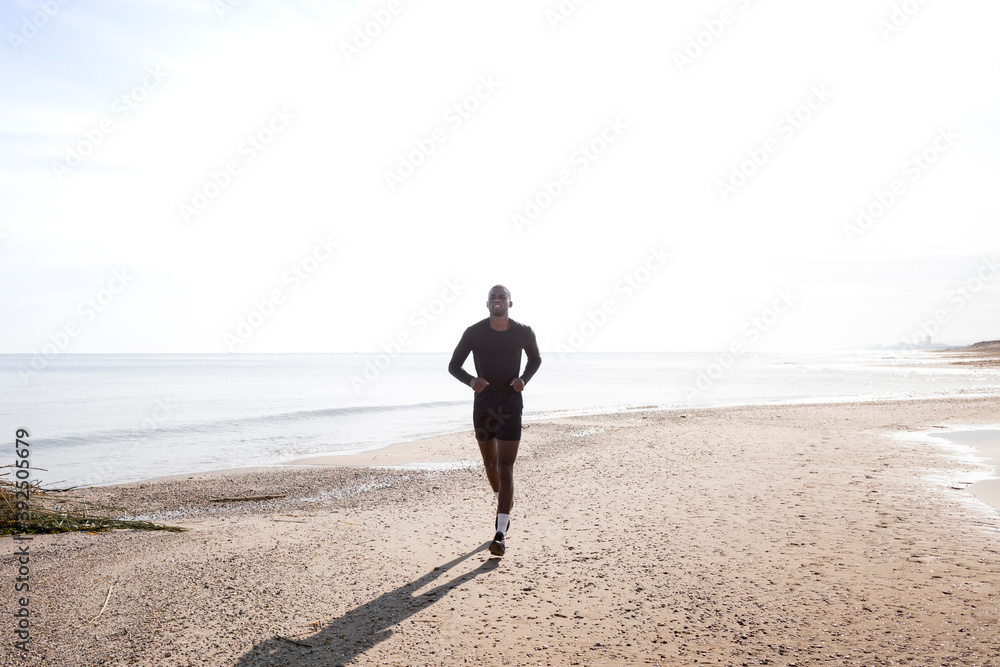 Black sportsman who practices running on the beach with a back light. Concept of health and sport. Black sportsman who practices running on the beach with a back light. Concept of health and sport.