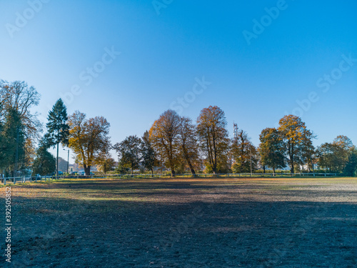 Empty paddock for horses with colorful fall trees around photo