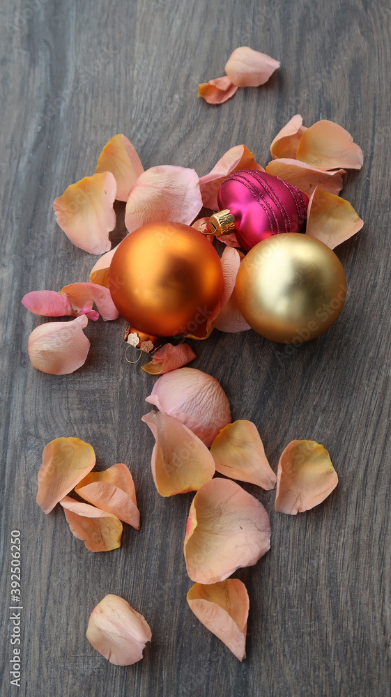beautiful shiny balls surrounded by rose petals on wooden tile