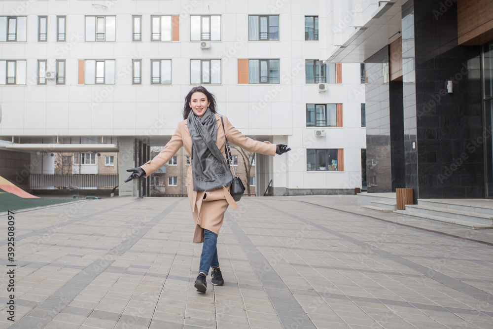 Happy european woman in coat walking in the atumn city