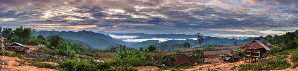 Akha village in the mountains of North Laos, sunset dramatic sky. Remote tribal village travel destination for tribal trekking, Akha ethnic group and minority.