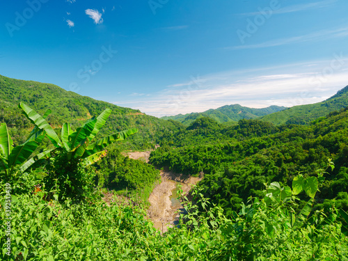 Remote valley in the mountains of North Laos, clear blue sky. Lush green canyon amid jungle. Travel destination for tribal trekking in Akha villages, Phongsaly region. photo