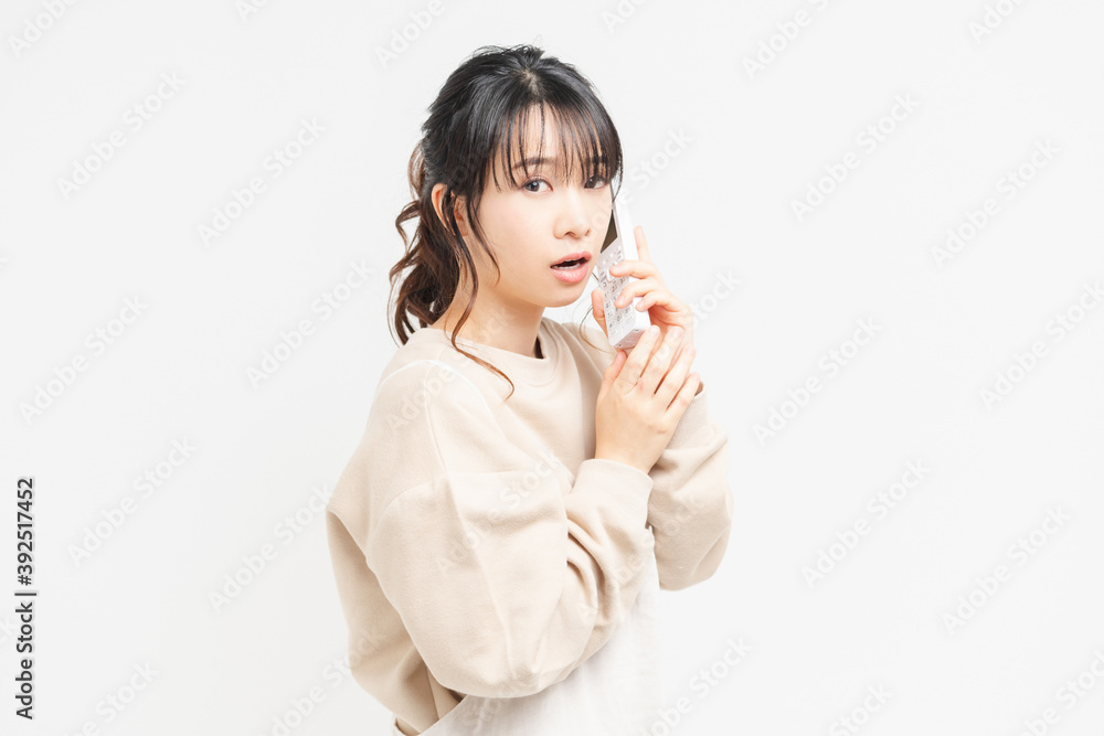 電話で話をしながら驚いてビックリしている若い女性