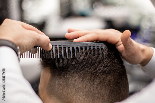 Barber's hands combing a Caucasian man's hair