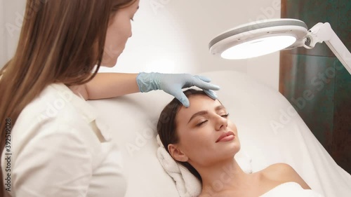 cosmetologist cheking female skin on face at beauty clinic