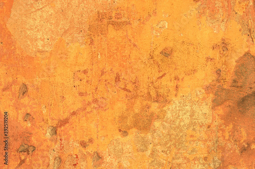 A large fragment of the orange clay wall of the old house with cracks and roughness, exfoliating part of the plaster. Vintage background. Rough flushed texture. Space to copy text.