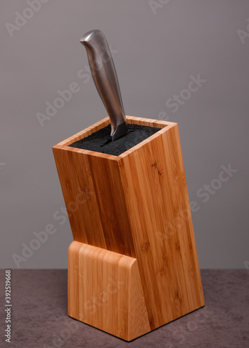 Wooden knife block with knife on grey background 