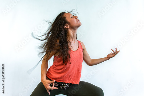 A trendy rock chick is seen celebrating life during an up tempo gym session, seen in an air guitar pose against a white wall with copy space
