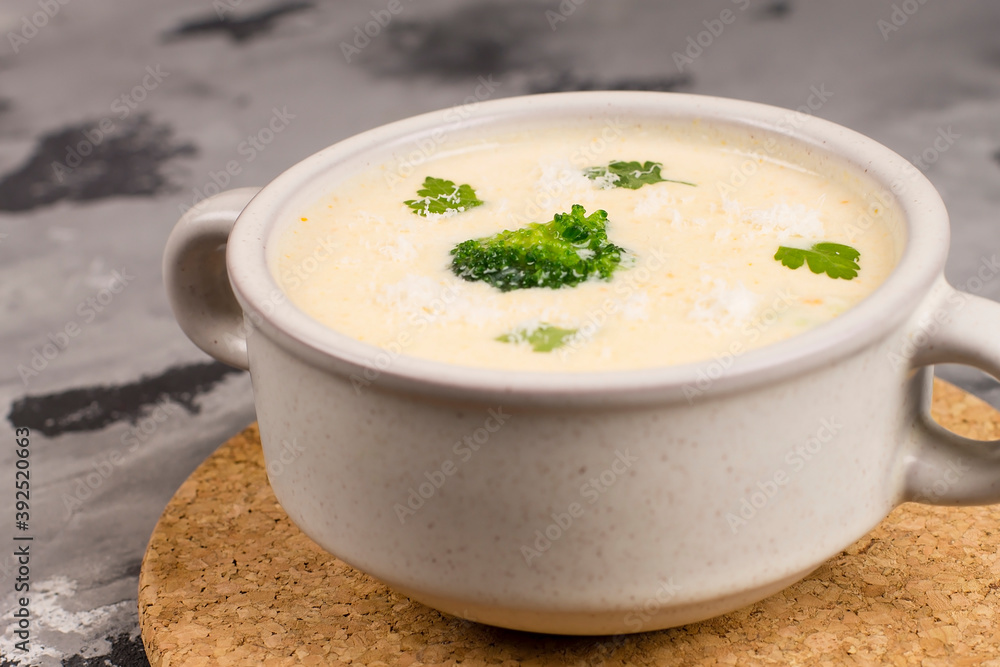 Cheese soup with herbs, in a plate, on a gray background, top view Cheese soup with herbs, in a plate, on a gray background, top view