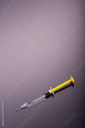 Yellow Syringe on glossy black background.  Copy Space. Dark side of Immunisation, vaccination, or drugs and darkness conmcept. photo