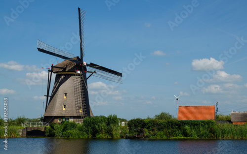 Kinderdijk  The Netherlands  August 2019. On a beautiful summer day a historic windmill  in perfect condition  in the Dutch countryside furrowed by canals lined with tall green grasses.