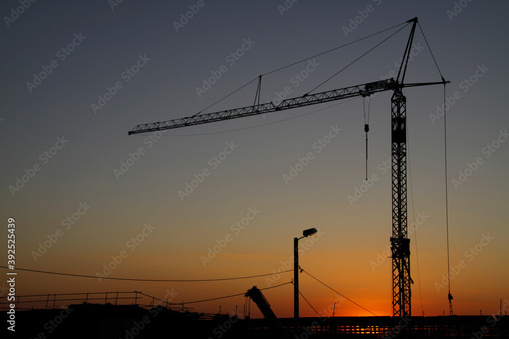 Construction crane working on road construction at sunset