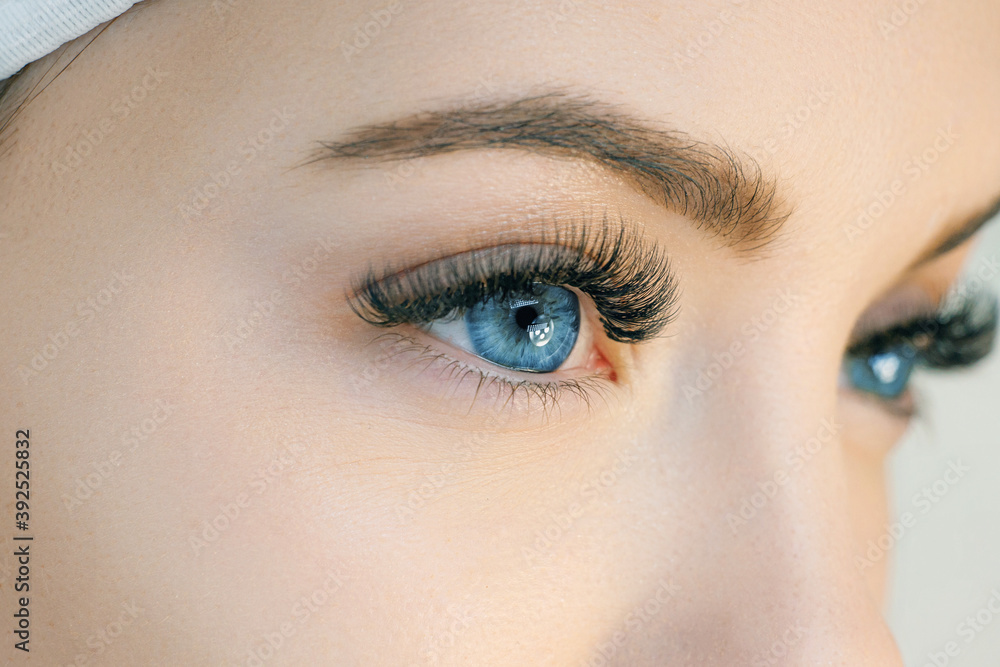 Close up view of beautiful blue female eye with long eyelashes. Eyelash extension procedure. Perfect trendy eyebrows. Good vision, contact lenses. Eye health and care. Close up view of beautiful blue female eye with long eyelashes. Eyelash extension procedure. Perfect trendy eyebrows. Good vision, contact lenses. Eye health and care.