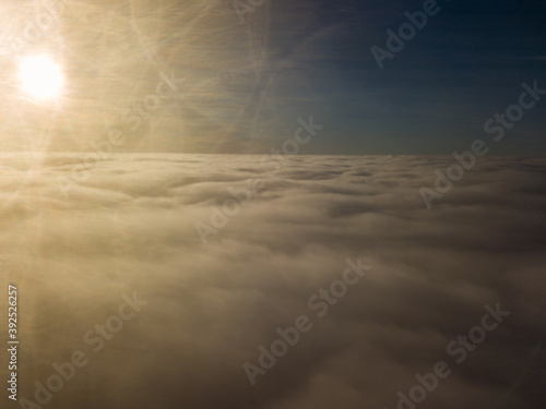 Aerial high flight over curly clouds. The sun's rays shine on the clouds.