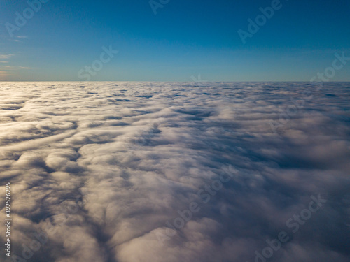 Aerial high flight over curly clouds. The sun s rays shine on the clouds.