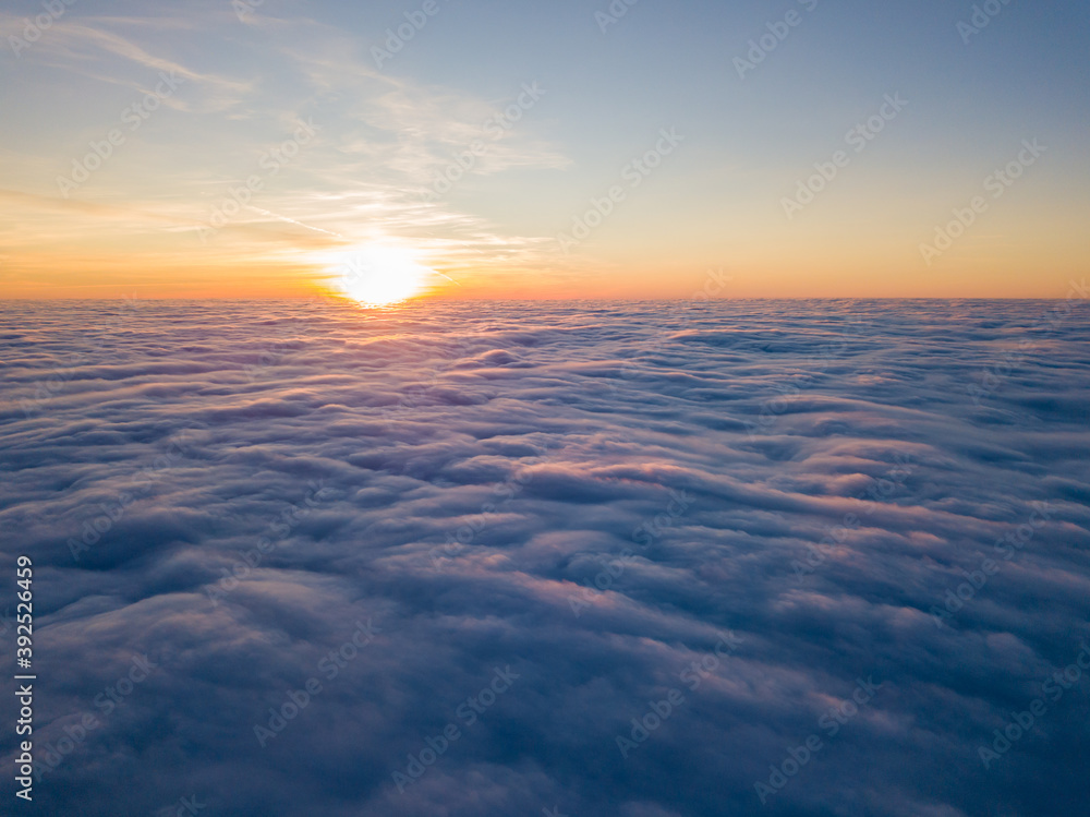 Fototapeta premium Sunset over curly clouds, aerial high flight. The last rays of the sun shine on the clouds.