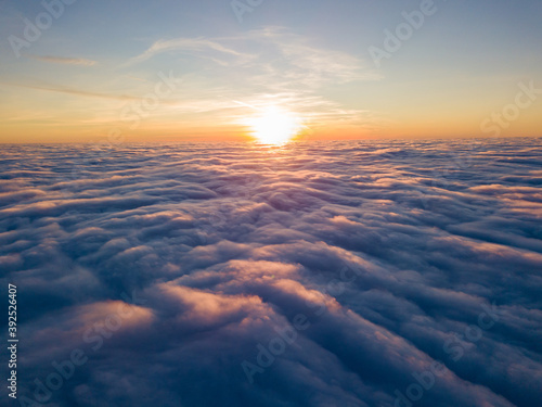 Sunset over curly clouds, aerial high flight. The last rays of the sun shine on the clouds.