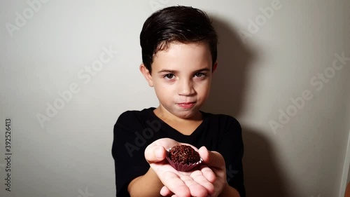 7 year old child showing a candy, eating a brigadeiro and leaving. photo