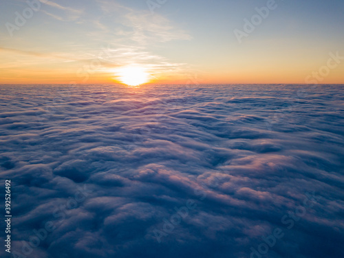 Sunset over curly clouds, aerial high flight. The last rays of the sun shine on the clouds.