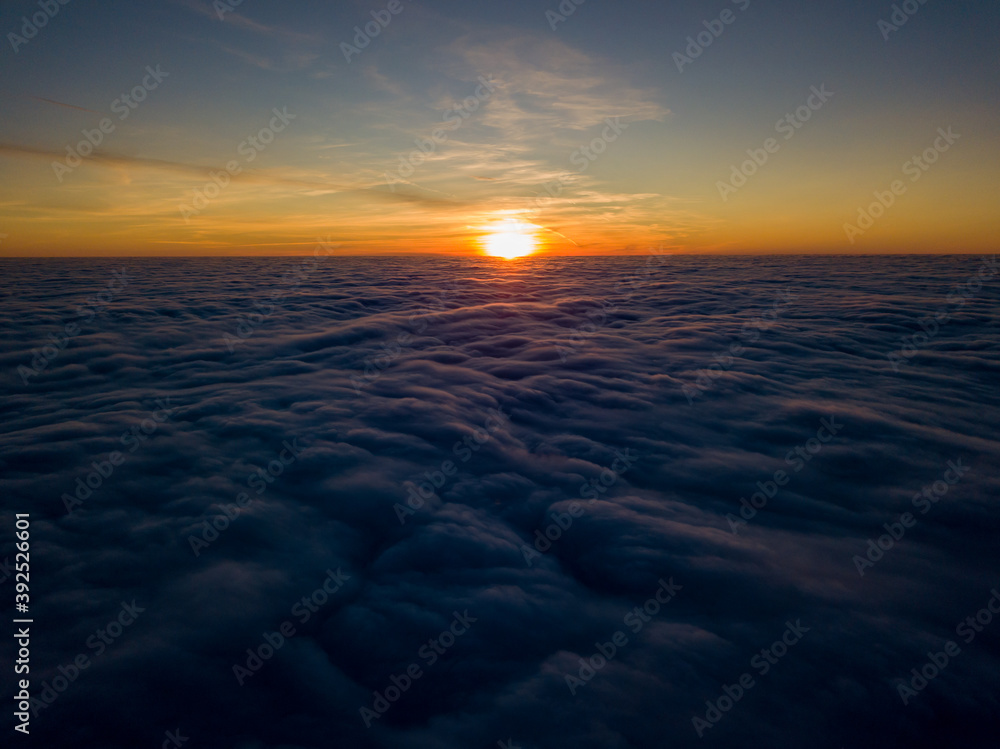 Sunset over curly clouds, aerial high flight. The last rays of the sun shine on the clouds.