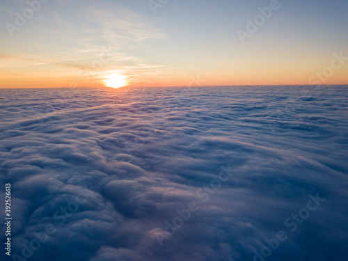 Sunset over curly clouds, aerial high flight. The last rays of the sun shine on the clouds.