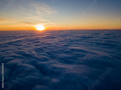 Sunset over curly clouds  aerial high flight. The last rays of the sun shine on the clouds.
