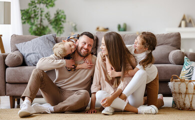 happy family mother father and children at home on floor next to sofa.
