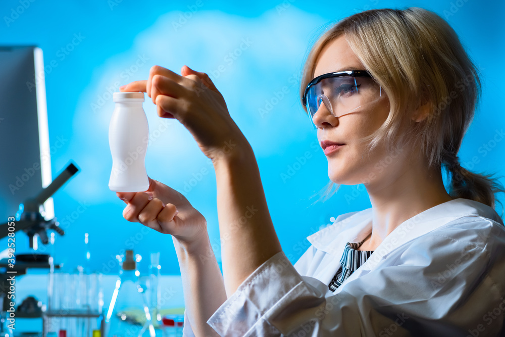 Probiotic yogurt. Laboratory assistant holds a white bottle in her