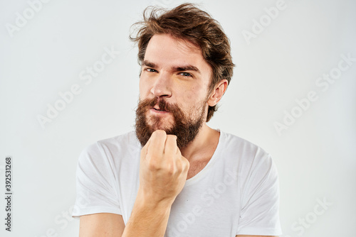 Bearded man gesturing with hands cropped view white t-shirt studio emotion light background