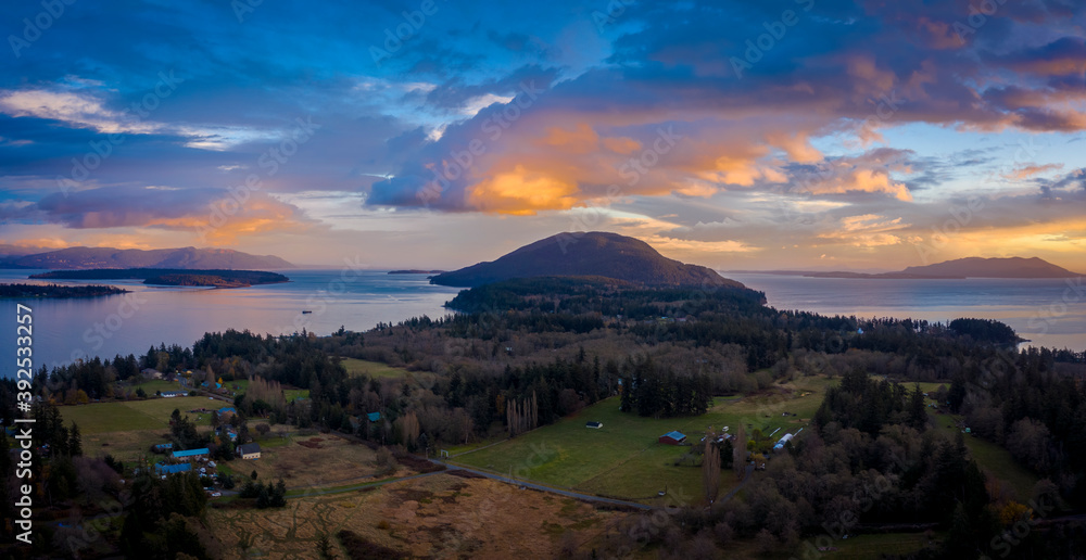 Panoramic Aerial Sunset View of an Island In the Pacific Northwest. Dramatic clouds highlight this drone shot of surrounding islands in the Salish Sea area of western Washington state. Lummi Island.