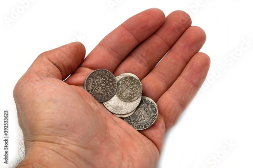 Ancient silver coins in hand on white background