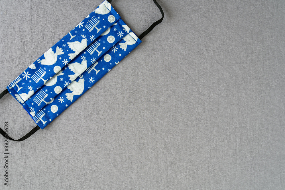 Handmade fabric mask on a silver background, celebrate Hanukkah with Jewish symbols on a blue mask
Handmade fabric mask on a silver background, celebrate Hanukkah with Jewish symbols on a blue mask