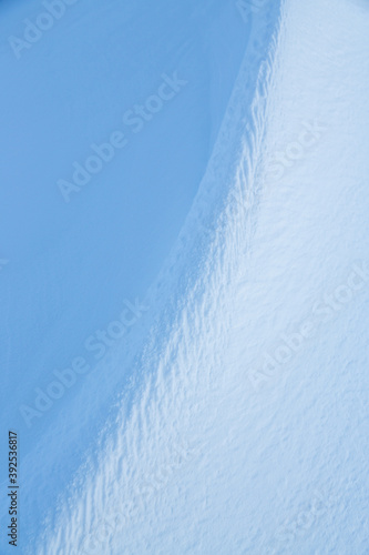 Snow texture. Wind sculpted patterns on snow surface. Wind in the tundra and in the mountains on the surface of the snow sculpts patterns and ridges (sastrugi). Arctic, Polar region. Winter background photo