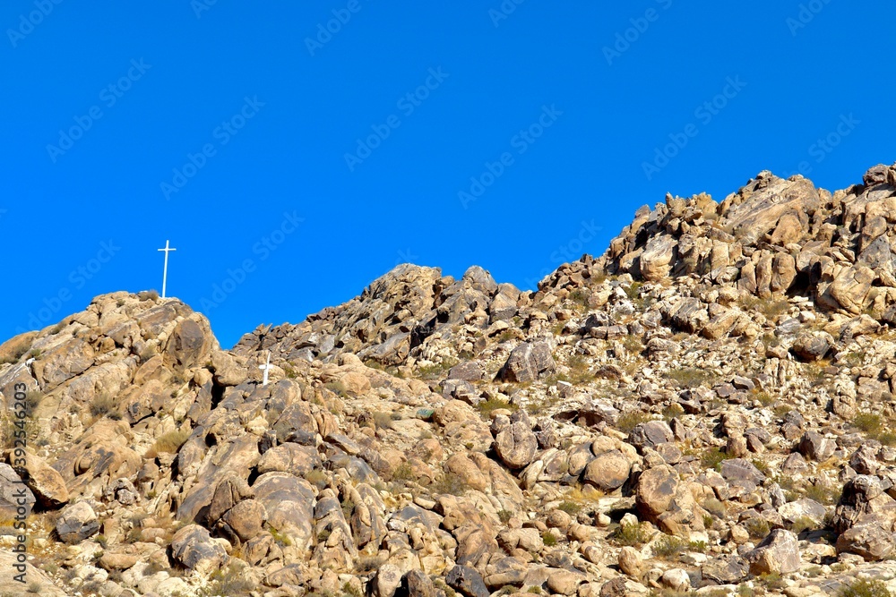 Fototapeta premium Religious Cross on Rocky Mountain in Desert City 
