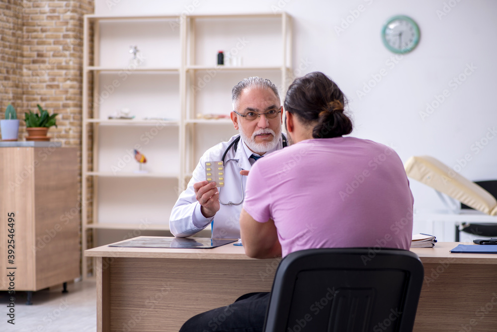 Young male patient visiting old male doctor Young male patient visiting old male doctor