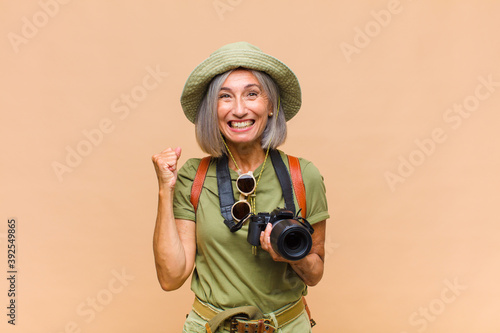 middle age woman feeling shocked, excited and happy, laughing and celebrating success, saying wow! photo