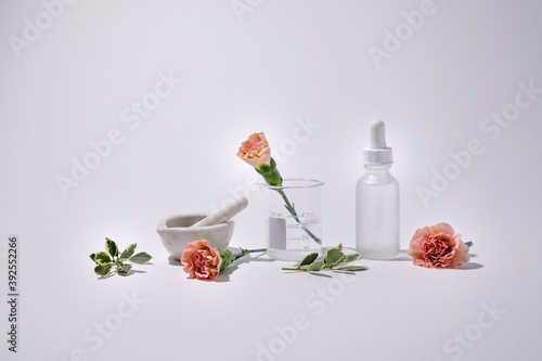 Cosmetic skin care product with pink flower on white background. Natural beauty concept with white mock up bottle .
