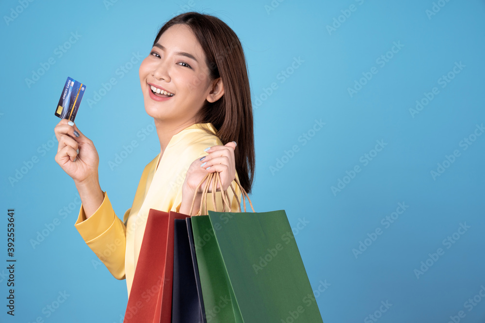 Young Asian woman enjoying shopping, Isolated on a blue background. Young Asian woman enjoying shopping, Isolated on a blue background.