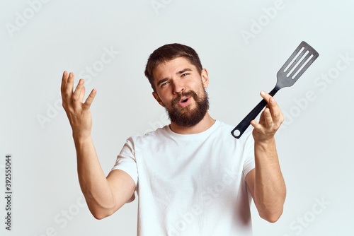 man with cooking shovel and white t-shirt close-up cropped view emotion gesturing with hand