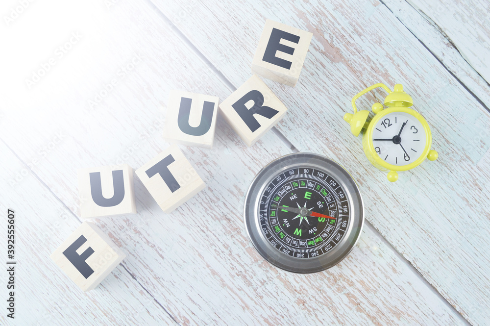 Top view of compass, clock and wooden cubes written with text FUTURE on a wooden background. Top view of compass, clock and wooden cubes written with text FUTURE on a wooden background.