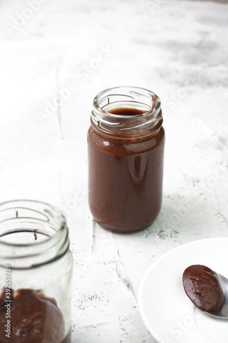 Chocolate Almond butter in jars that focus on the full one in isolated white background. Selective focus